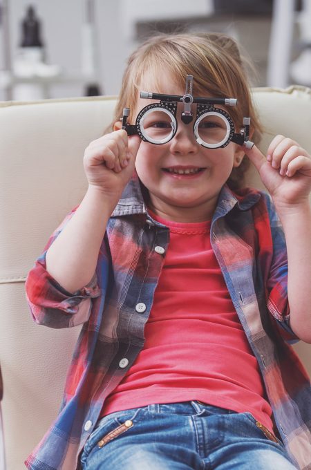 Little boy looking at camera and smiling while sitting on chair at the ophthalmologist